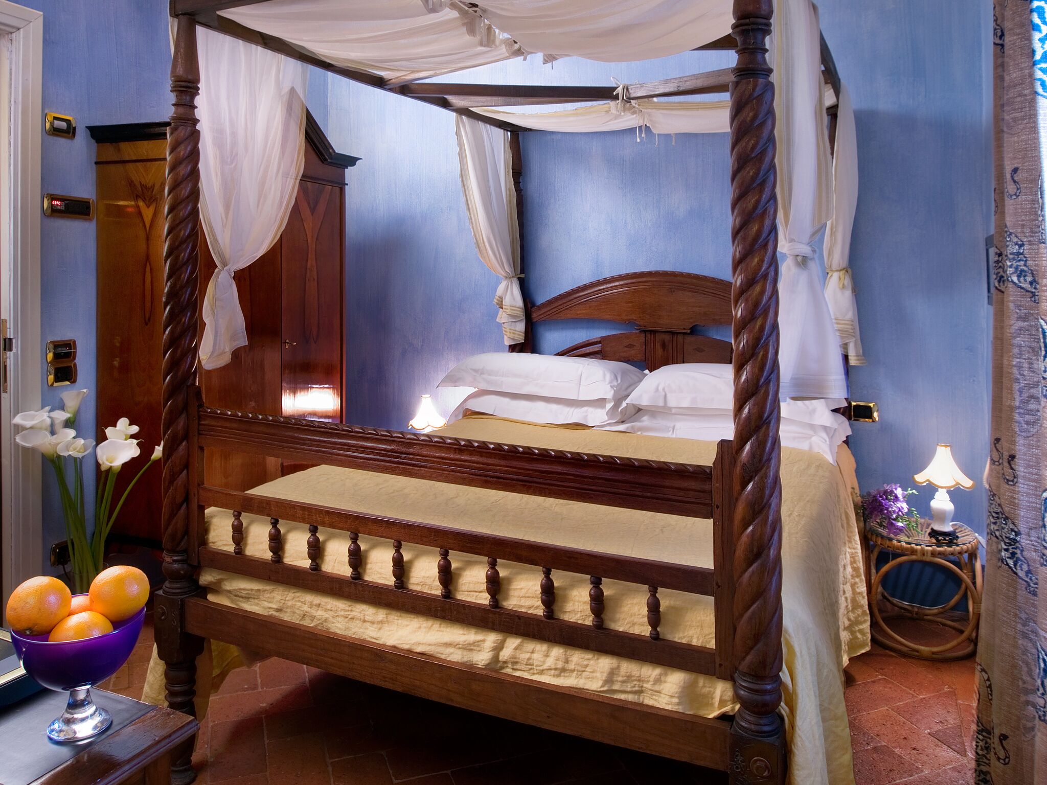 A four-poster canopy bed with a wooden frame and white bedding.