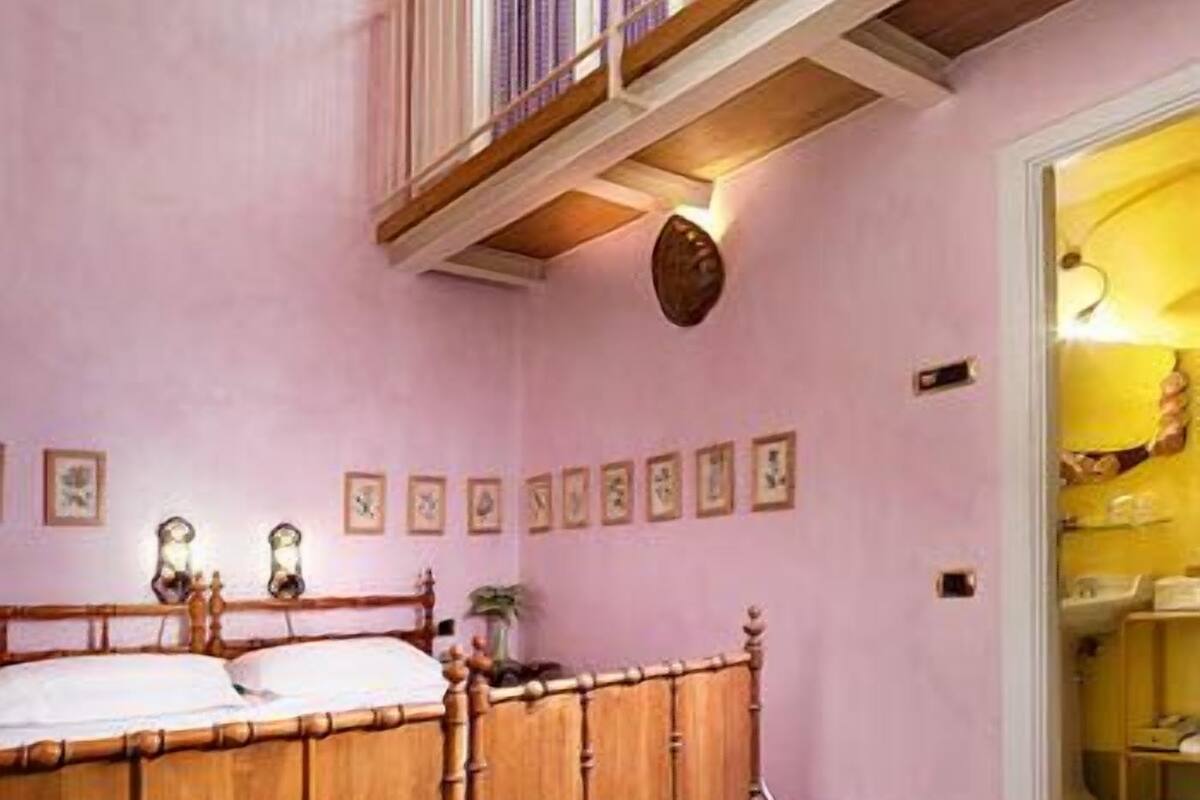 Een slaapkamer met een houten bed, een klein balkon en een deur naar een badkamer.