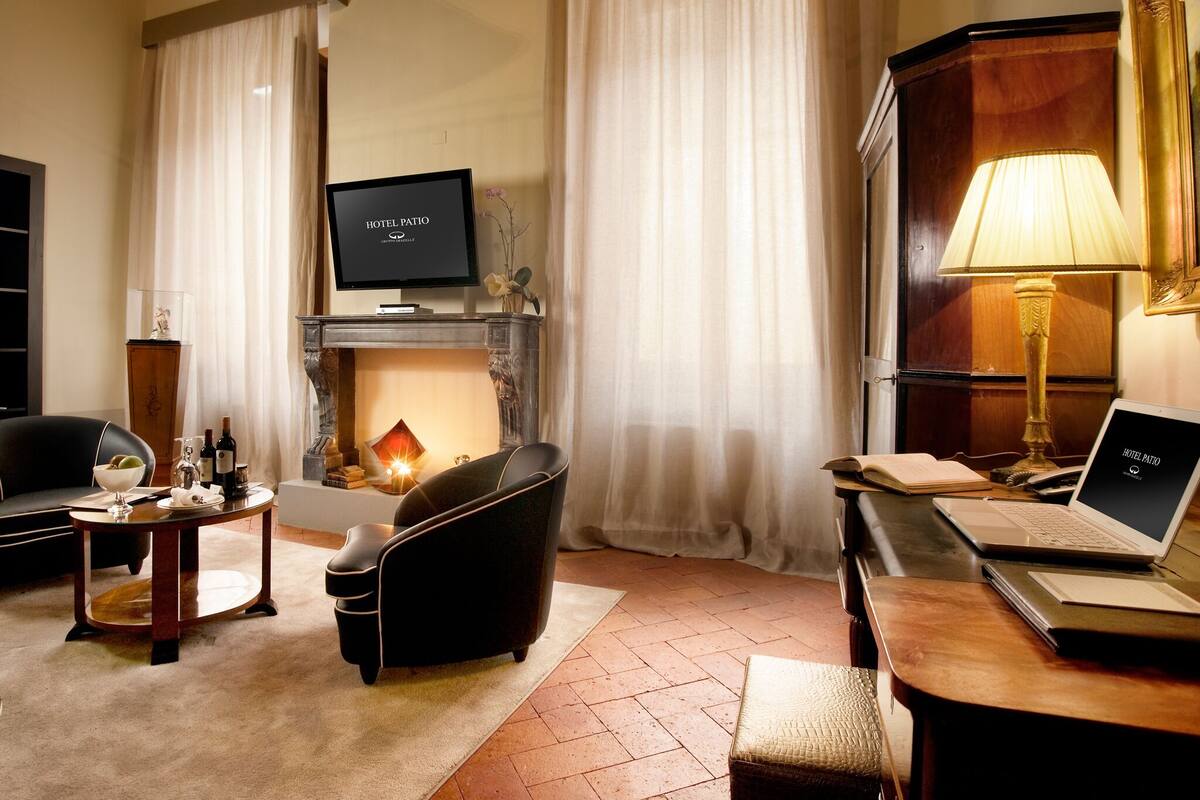 Een hotelkamer met een open haard, een televisie, een laptop en een eettafel met stoelen.