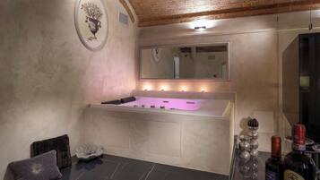 Ein Spa-Bereich mit einer großen Badewanne, einem Spiegel und einem an der Wand befestigten Kunstwerk.