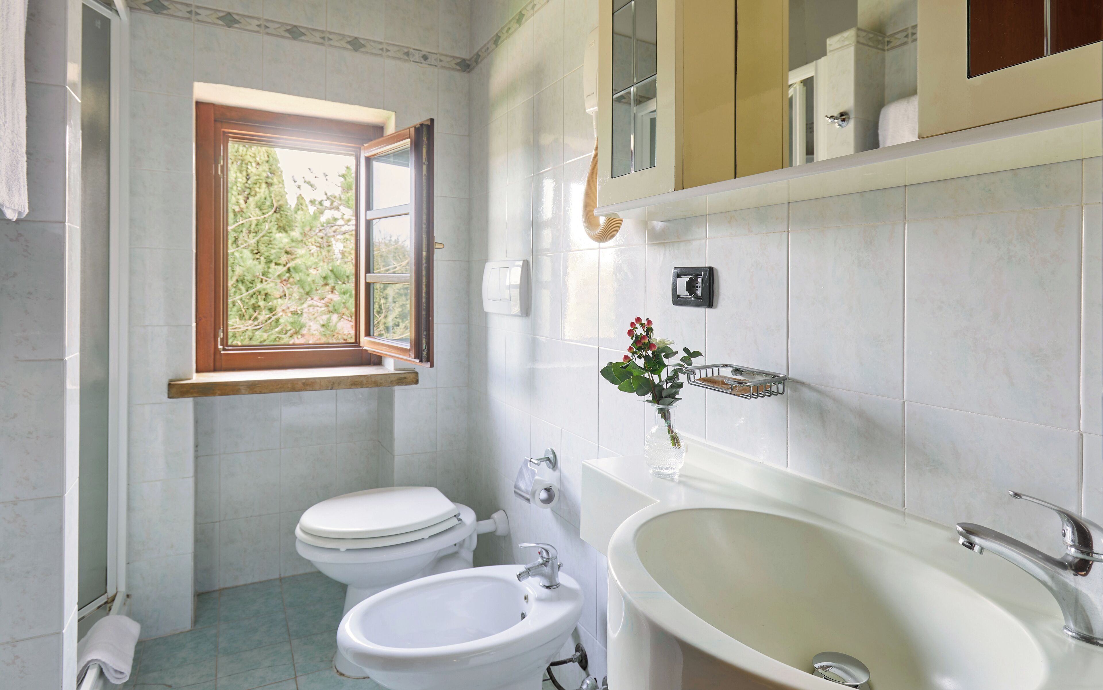 A bathroom with two toilets, a sink, and a bathtub.