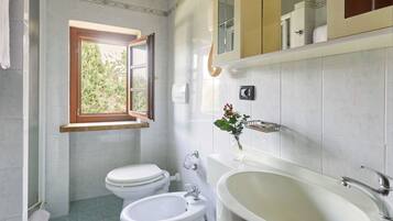 Ein Badezimmer mit zwei Toiletten, einem Waschbecken und einer Badewanne.