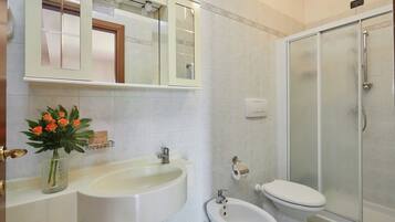 A bathroom with a sink, mirror, toilet, and shower.