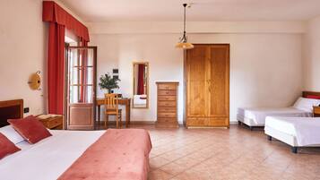 Une chambre d’hôtel avec deux lits, un bureau avec une chaise, une armoire en bois et un grand miroir.