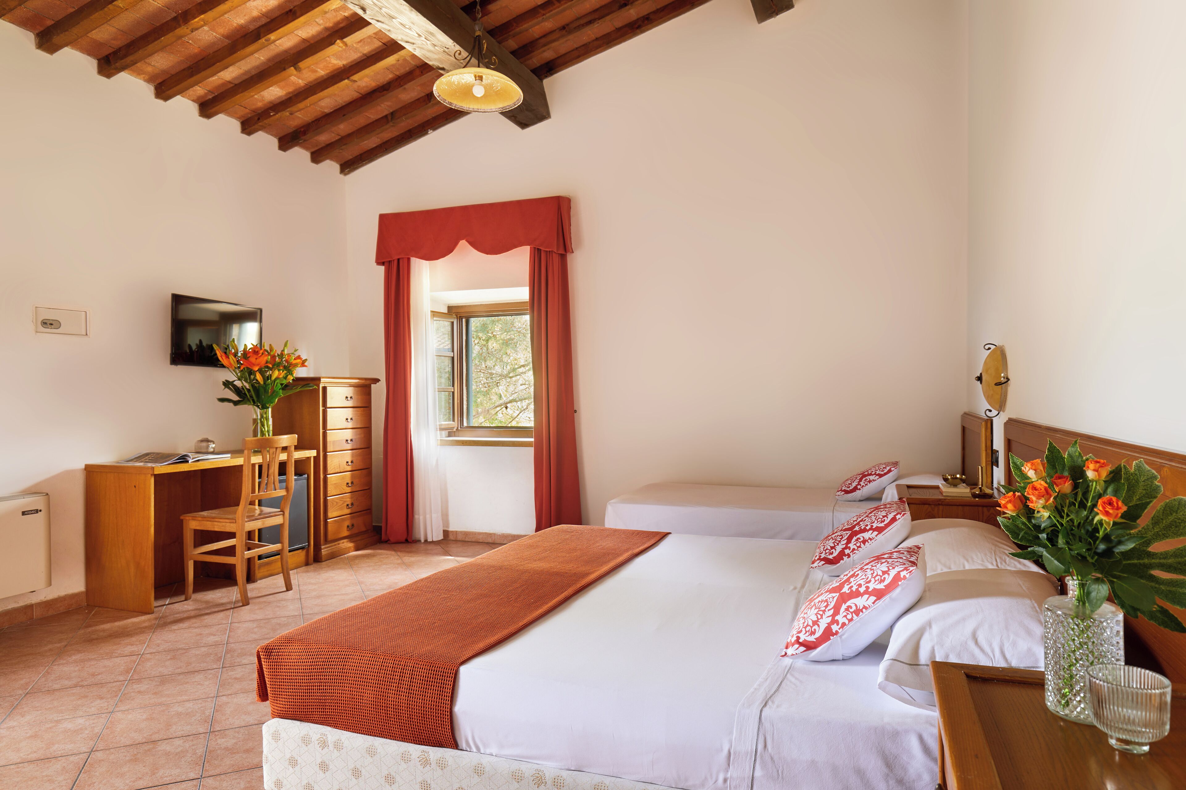 Ein Schlafzimmer mit Bett, Schreibtisch, Stuhl, Kommode und einem Fenster mit Vorhängen.