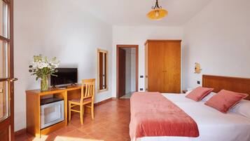 Un dormitorio con una cama, un escritorio con computadora, una silla y un televisor.