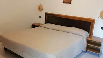 Une chambre à coucher avec un grand lit, une tête de lit en bois, des tables de chevet, une horloge murale et un tableau encadré.