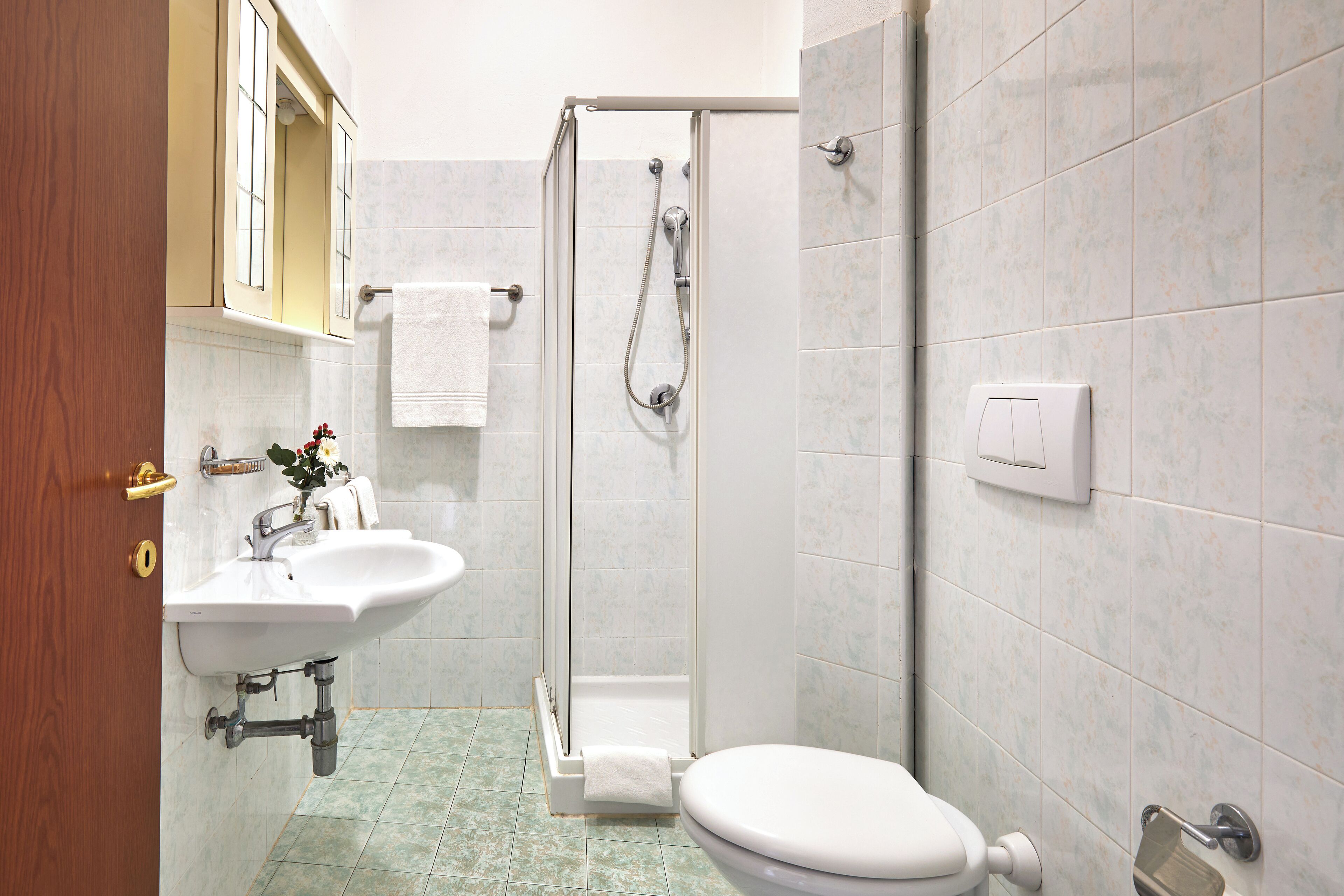 A bathroom with a sink, toilet, shower, and a towel rack.