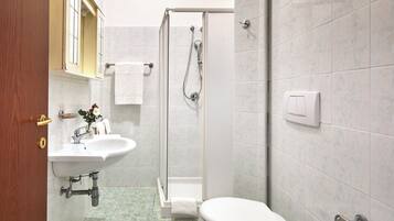 A bathroom with a sink, toilet, shower, and a towel rack.