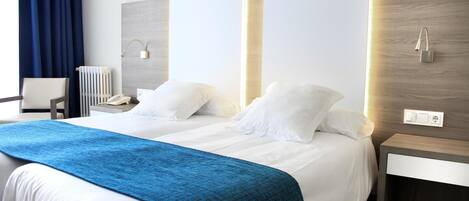 A hotel room with a large bed, two bedside tables, a chair, and a radiator.