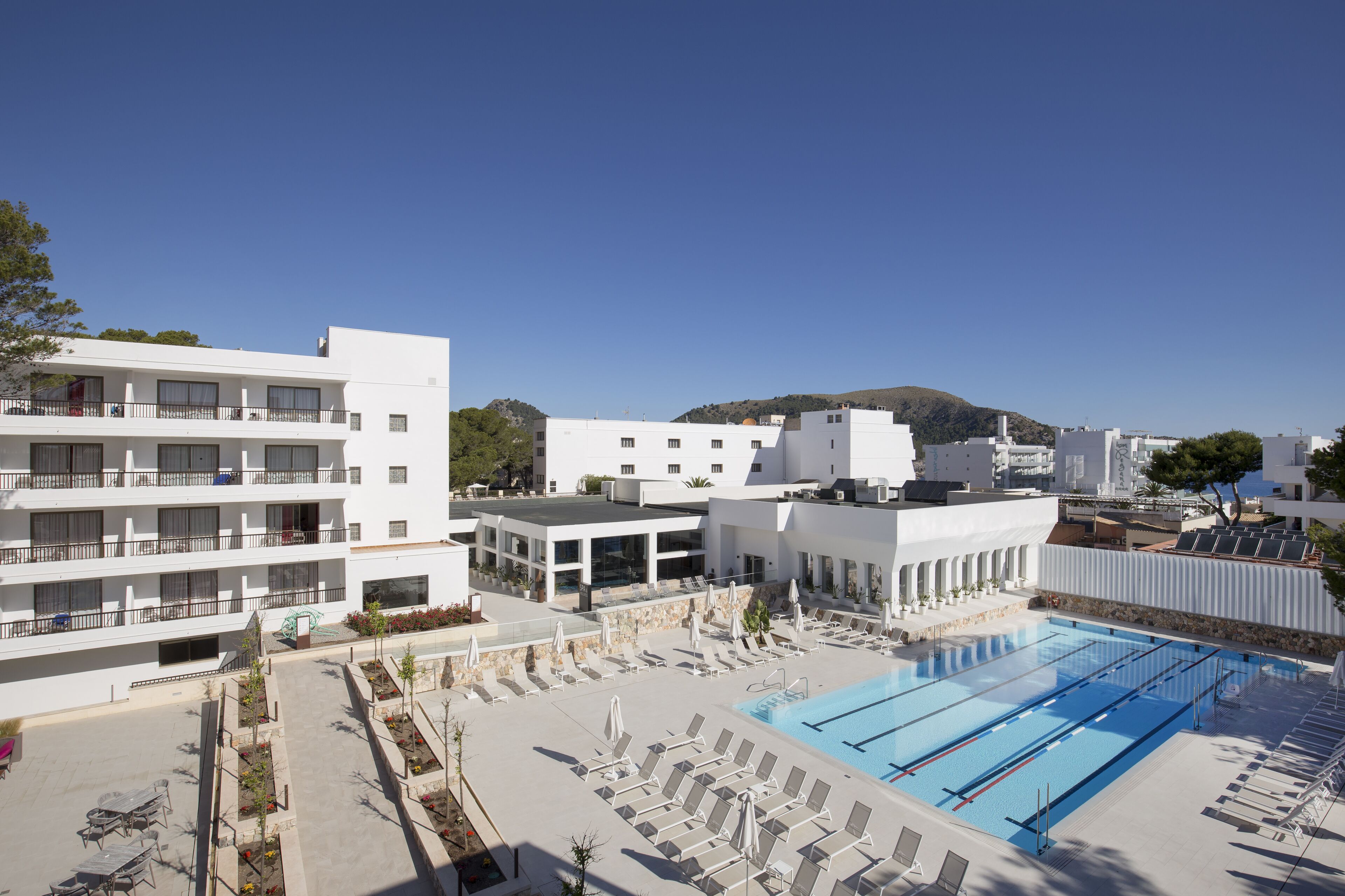 Un hotel con piscina, varios balcones y vistas a una colina.