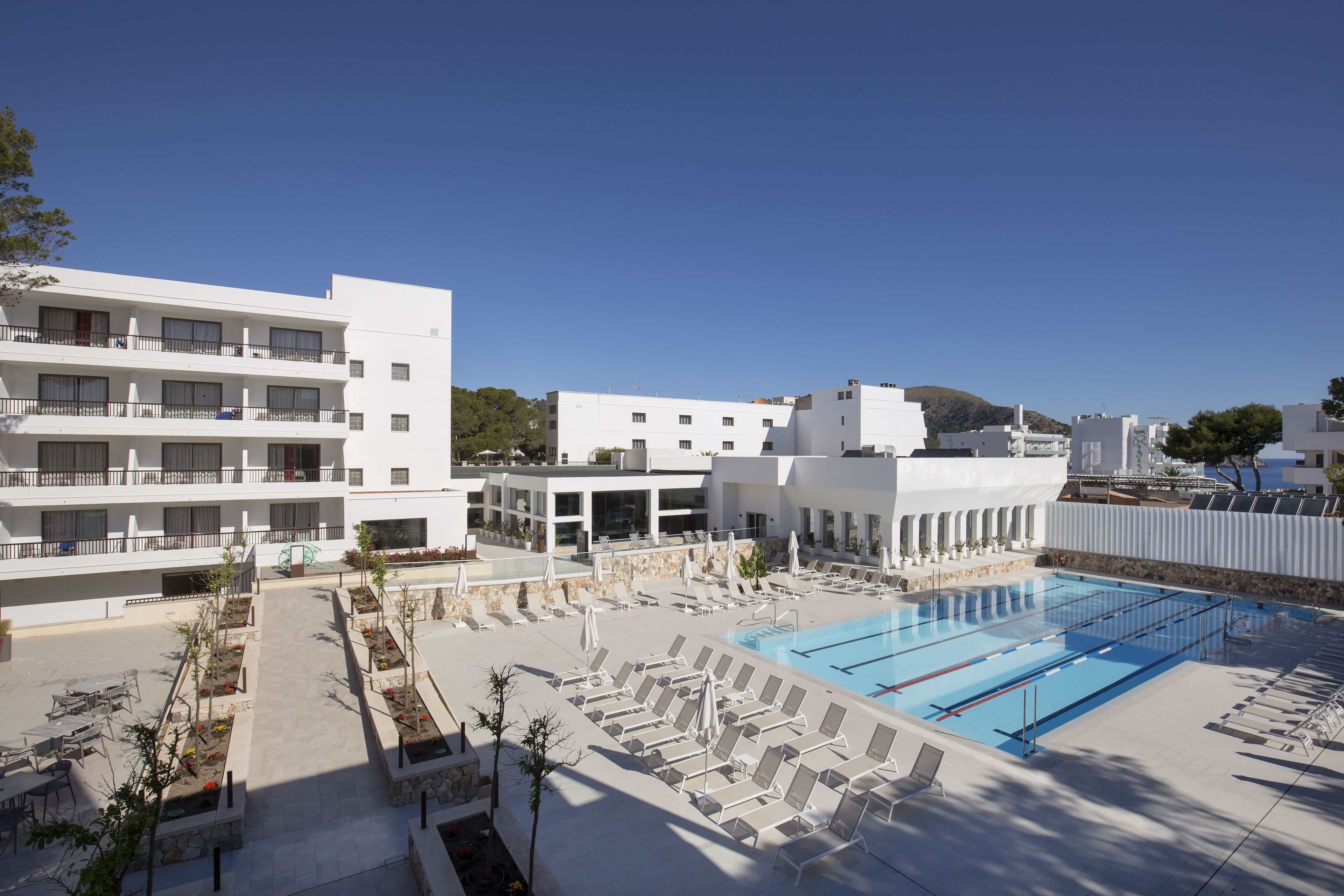 Un resort con piscina, lettini e cielo sereno.