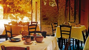 A cozy outdoor dining area with stone walls and wooden chairs, featuring a table set for tea service. - Relais La Torre (Arezzo)