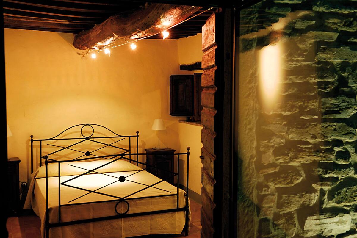 A bed with a metal frame, a wooden headboard, and a wall-mounted nightstand.