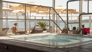A pool area with lounge chairs and umbrellas, overlooking a body of water. - Hotel Voramar Mallorca (Son Servera)