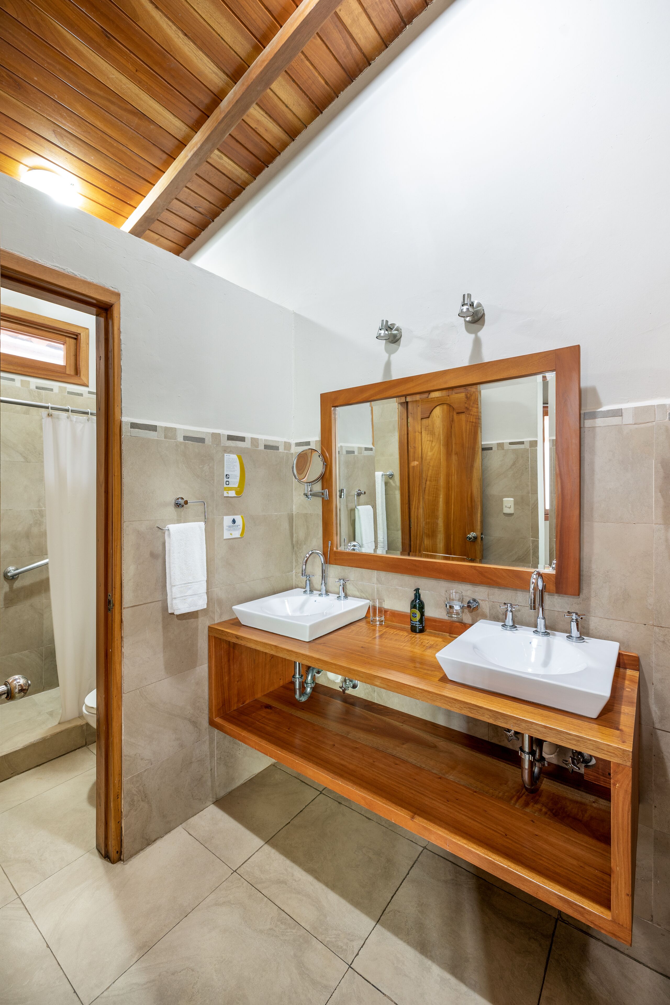 A bathroom with two sinks, wooden vanity, and a large mirror.