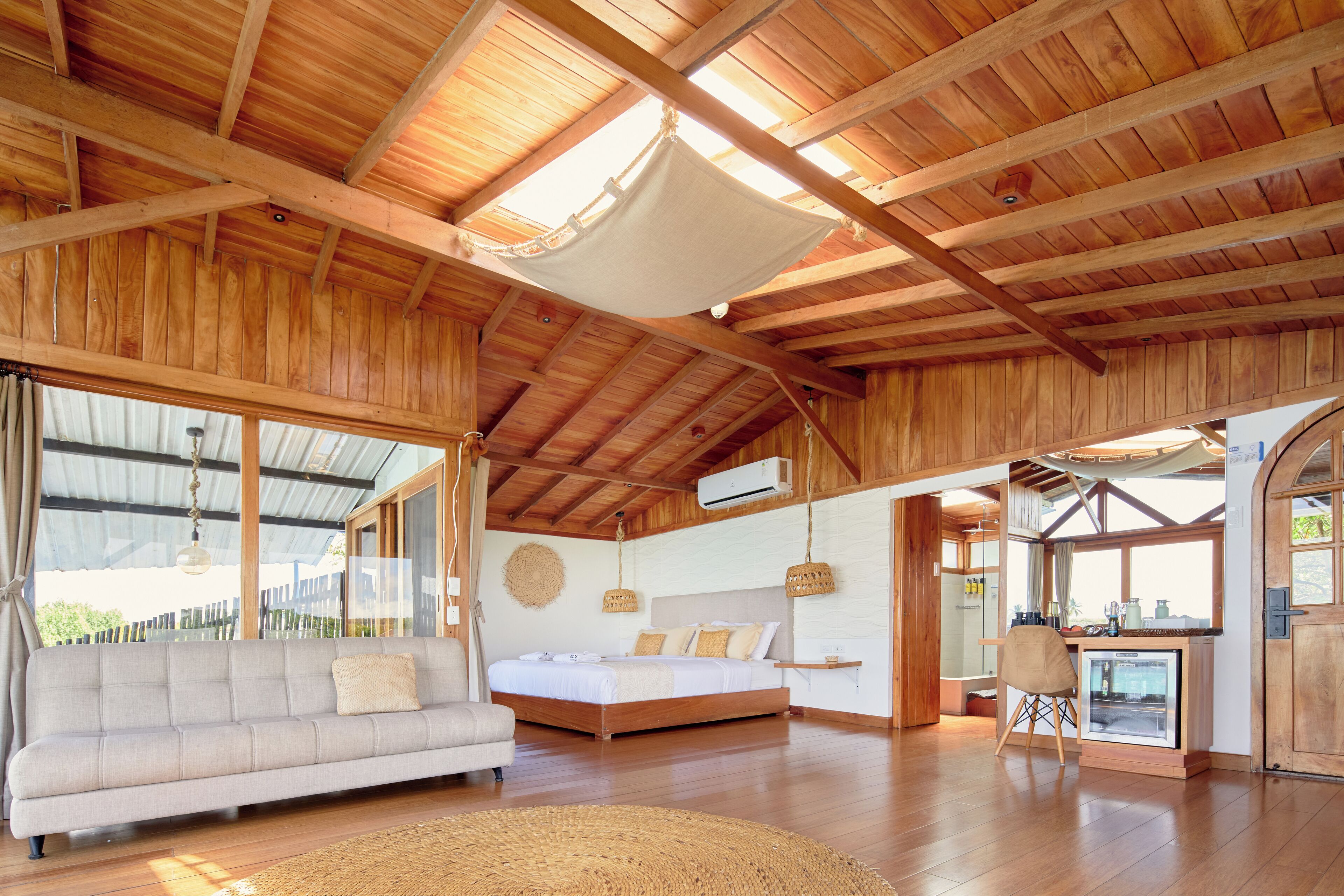 A spacious room with a large bed, a sofa, and a dining area with a refrigerator.