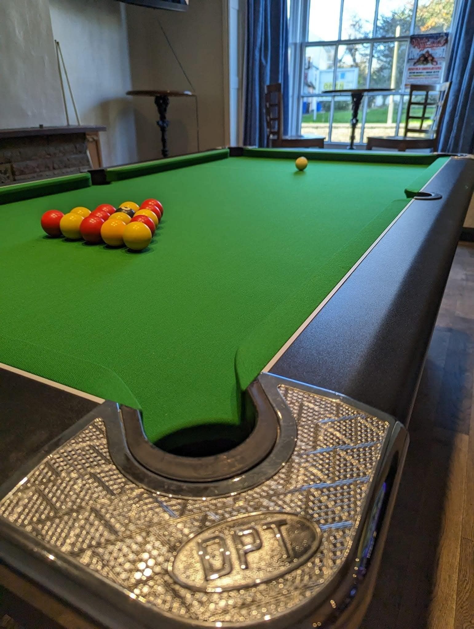 A pool table with balls, a cue stick, and a BPT logo on the table's edge.