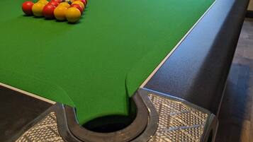 A pool table with balls, a cue stick, and a BPT logo on the table's edge.
