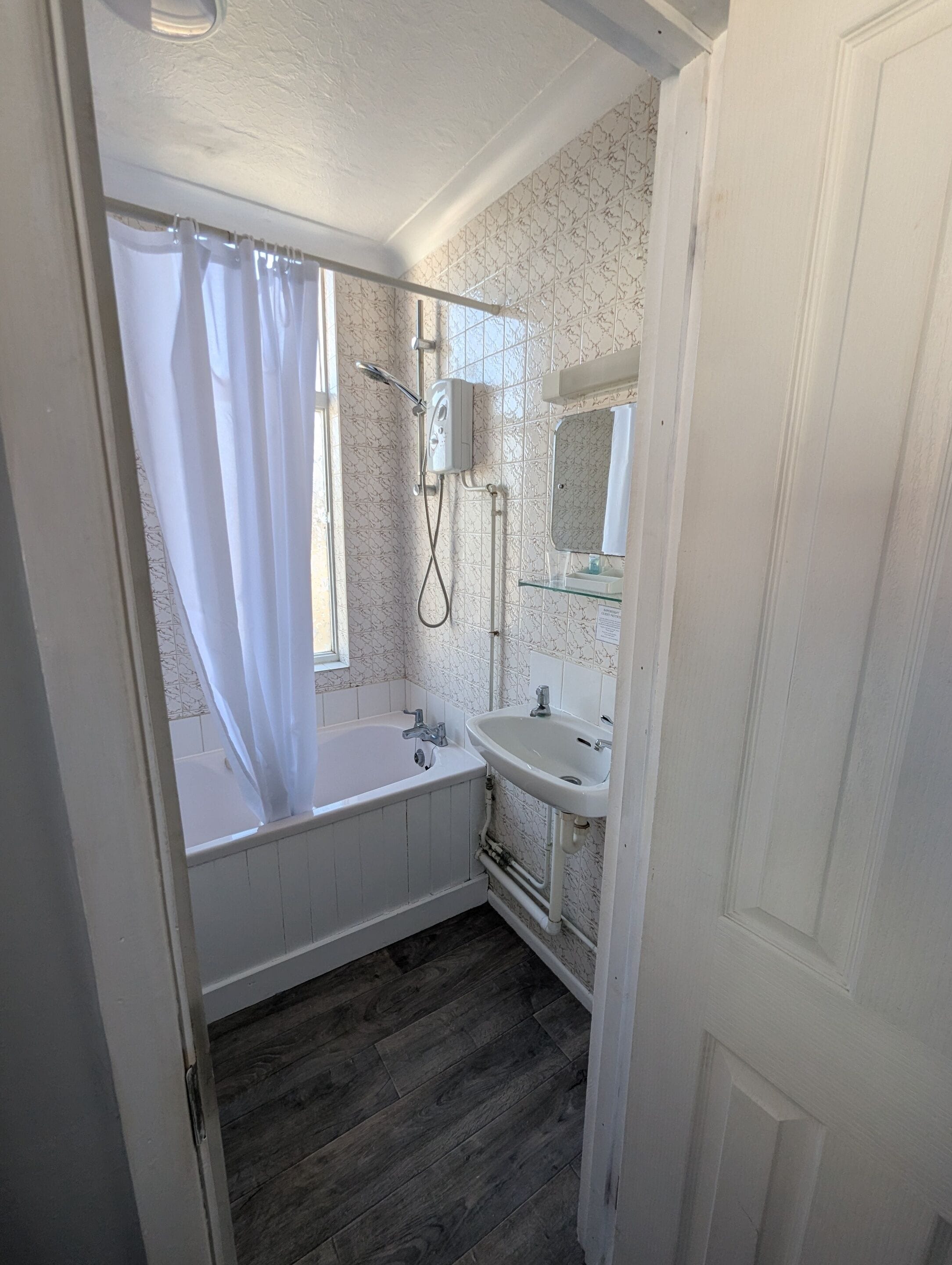 Een badkamer met een bad, douche, wastafel en spiegel.