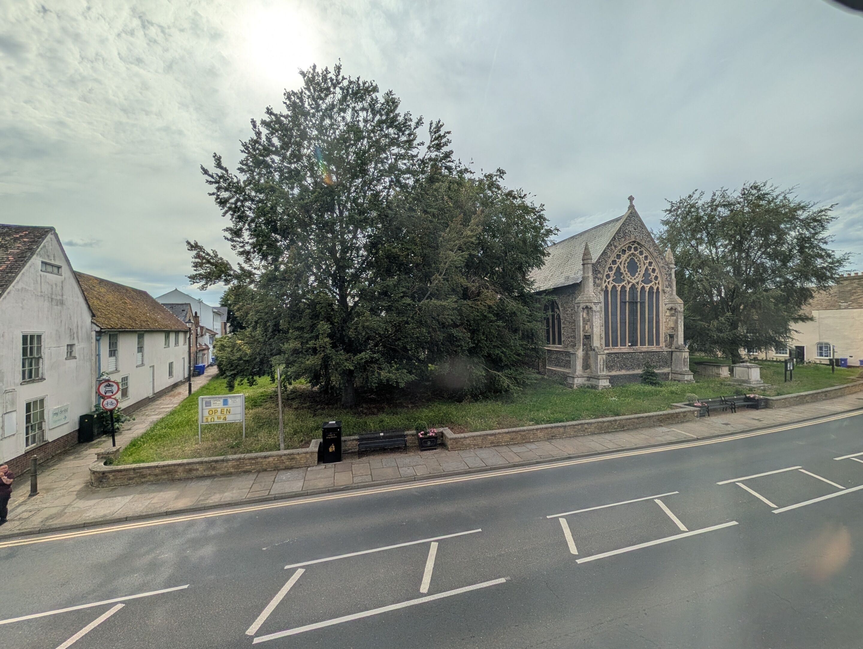 A street with a church, a bench, and a sign indicating the church is open to the public.