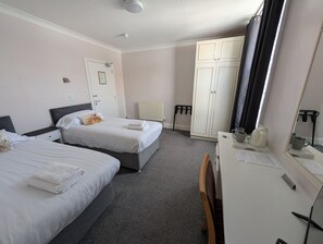 Ett hotellrum med två sängar, ett skrivbord, en garderob och ett element.