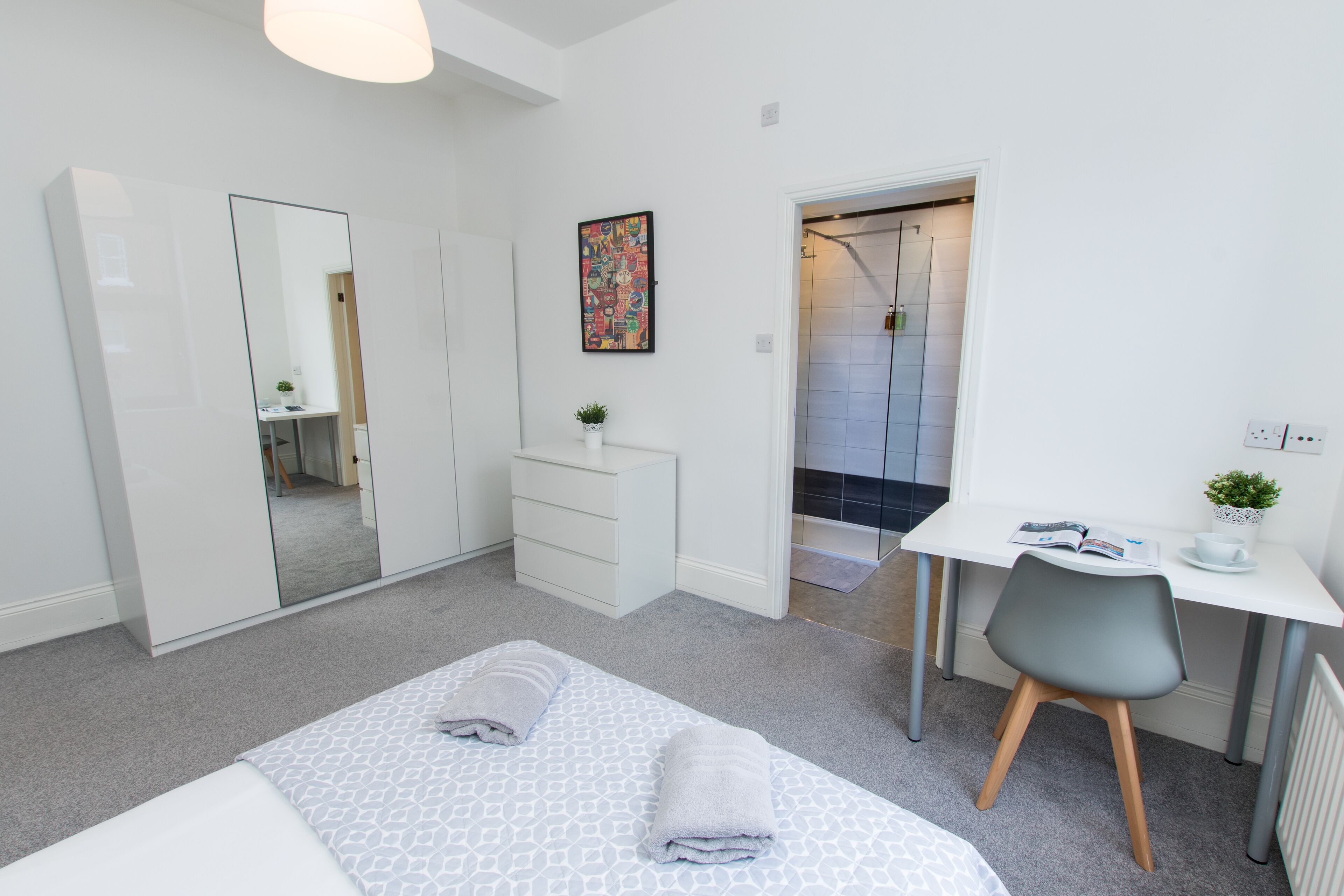 Une chambre moderne avec un grand lit, un bureau et un espace douche.