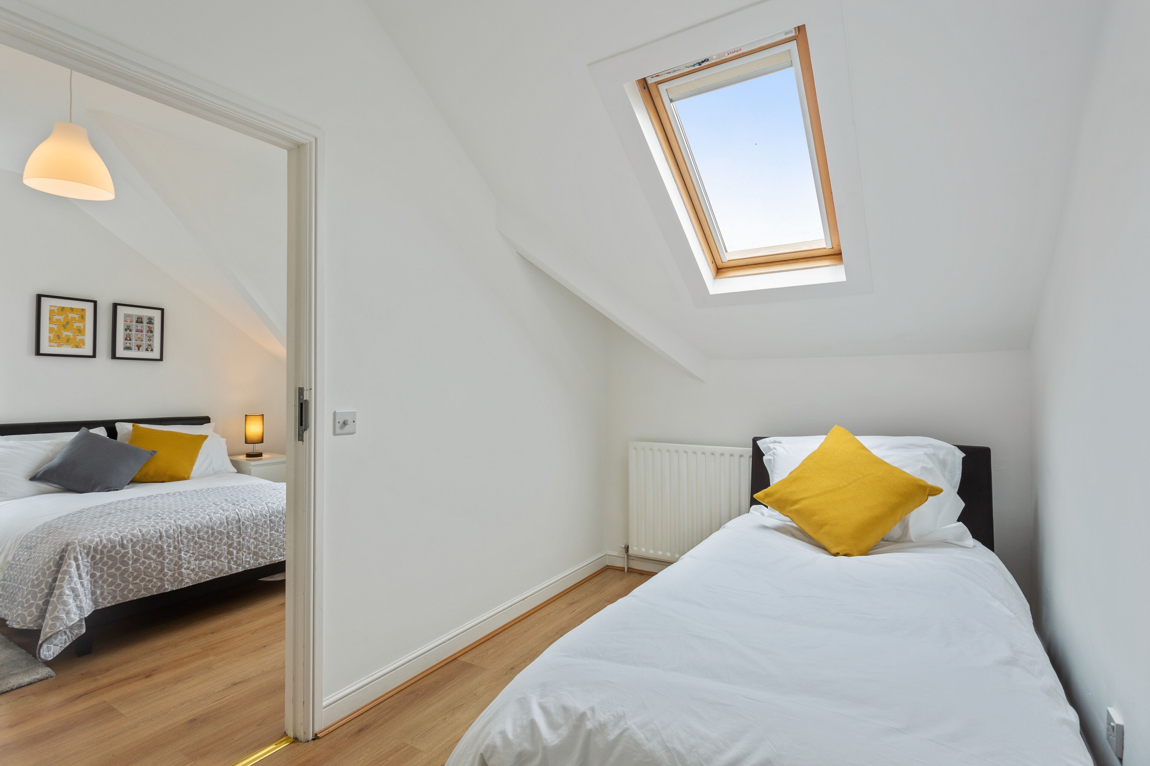 Een slaapkamer met twee bedden, een dakraam en een radiator.