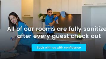 A hotel room with a modern kitchen, a dining area, and a living space. The room is well-lit with natural light.