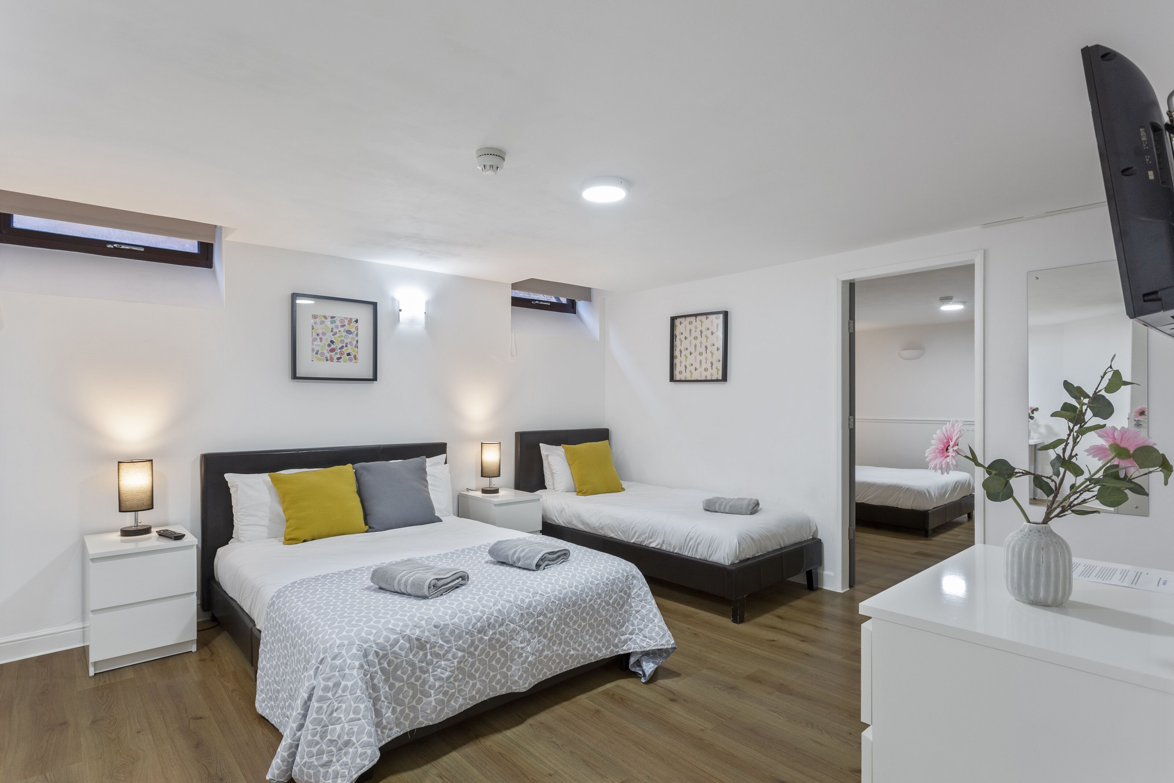 Una camera d'albergo moderna con due letti, una scrivania, uno specchio e una TV.