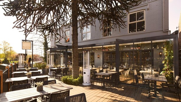 An outdoor dining area with tables and chairs, a large tree, and a building with a sign that reads "GUSTO". - River Rooms Nottingham (Nottingham)