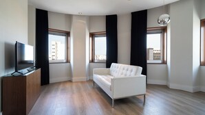 Ein modernes Wohnzimmer mit einem weißen Sofa, einer Holzhocker und einem Flachbildfernseher.