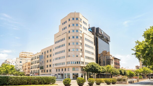 Ein mehrstöckiges Hotel mit modernem Design, das ein markantes 'X'-Logo an der Fassade zeigt.