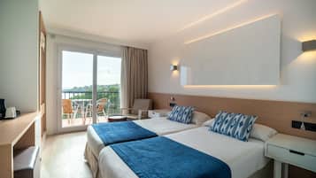 A hotel room with two beds, a desk, a chair, and a balcony with a view.