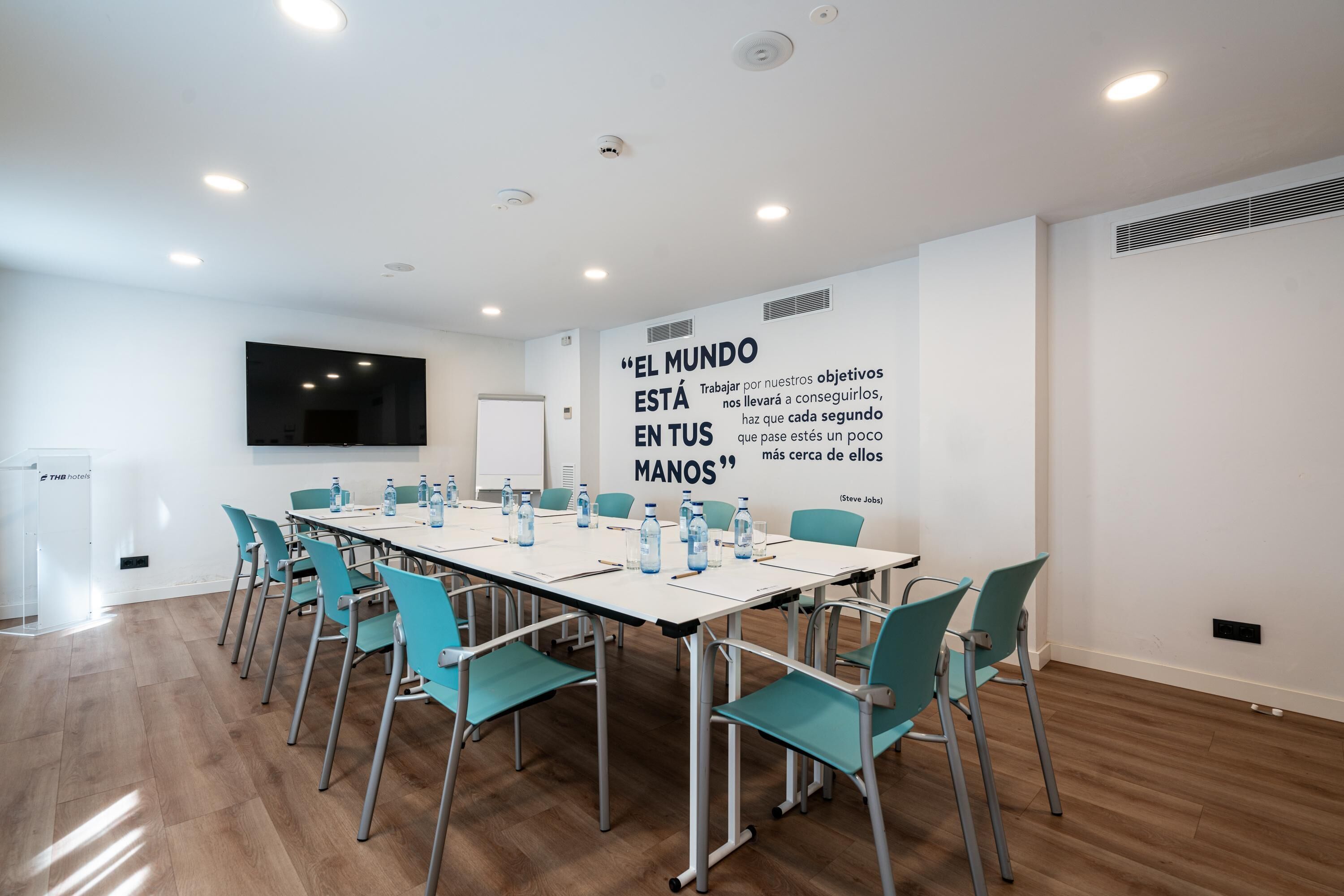 A conference room with a long table, teal chairs, and a motivational quote on the wall.
