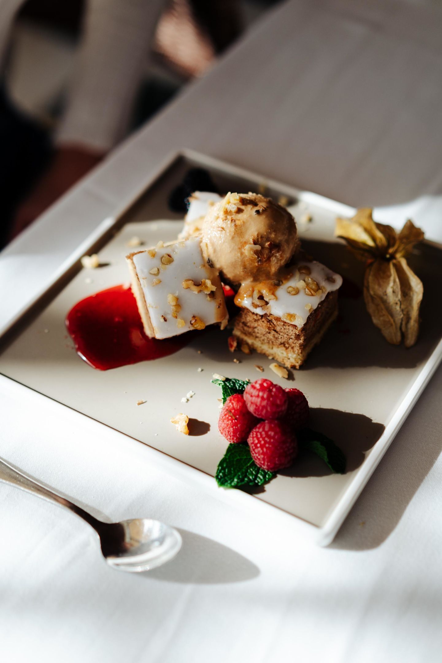 Un plato de postre con helado, pastel y frambuesas sobre un plato blanco.