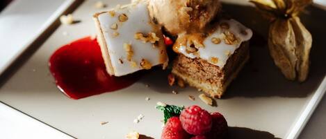 A dessert plate with ice cream, cake, and raspberries on a white plate.