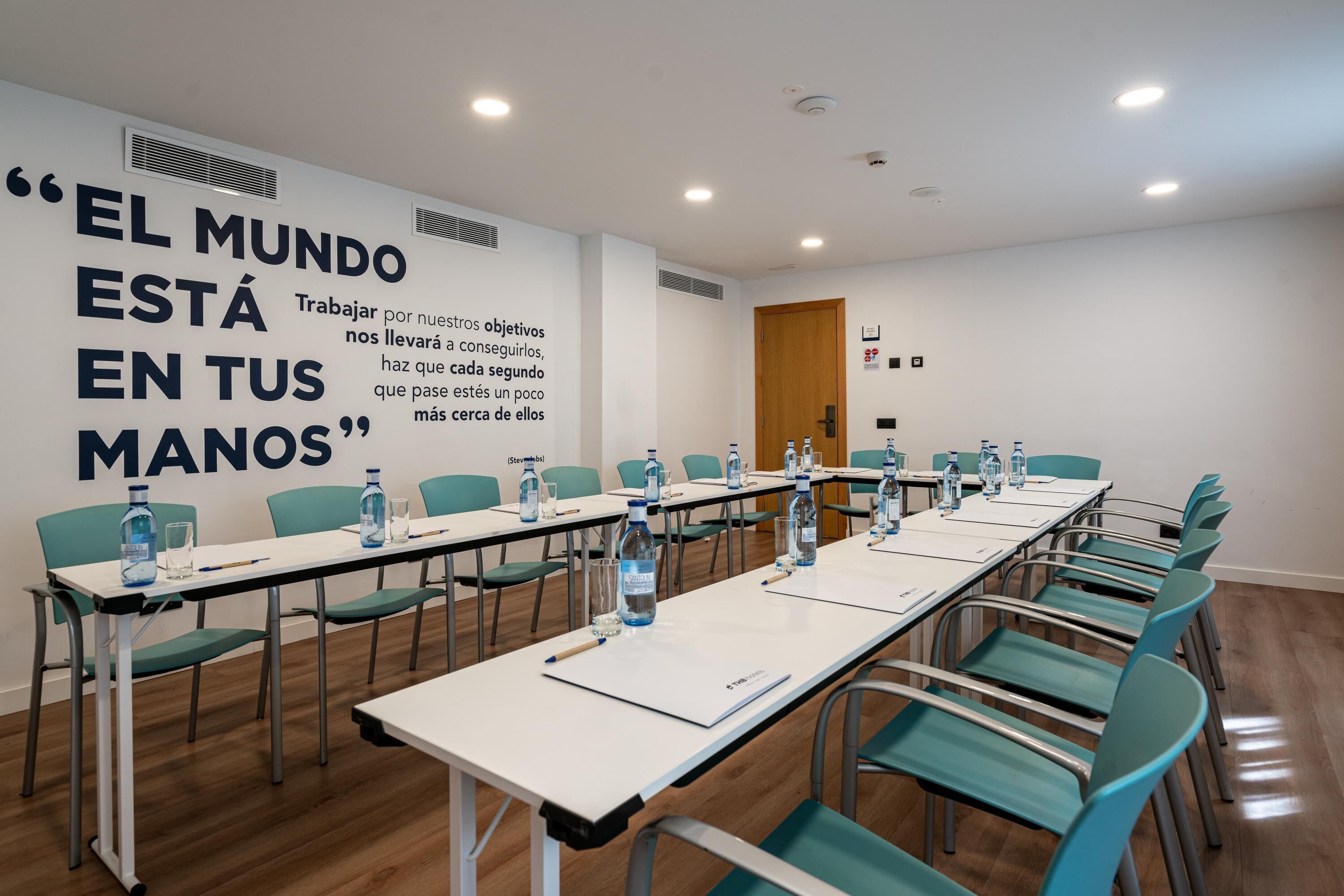 A conference room with tables, chairs, and water bottles.