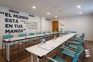 Un salón de conferencias con mesas, sillas y botellas de agua.