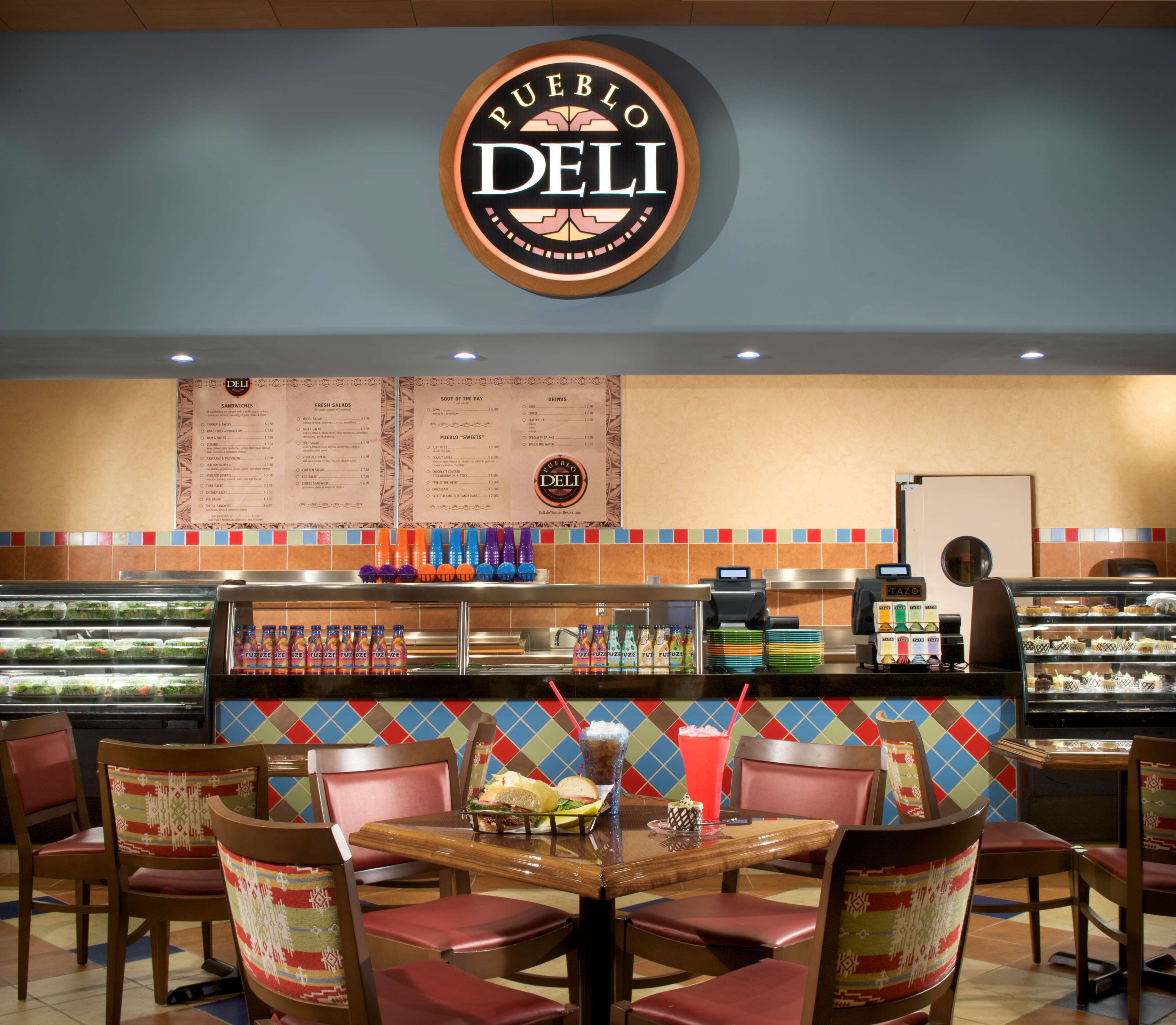 A restaurant interior with a central counter, menu boards, and seating area.