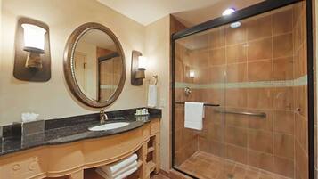 A bathroom with a large mirror, a sink, and a glass-enclosed shower.