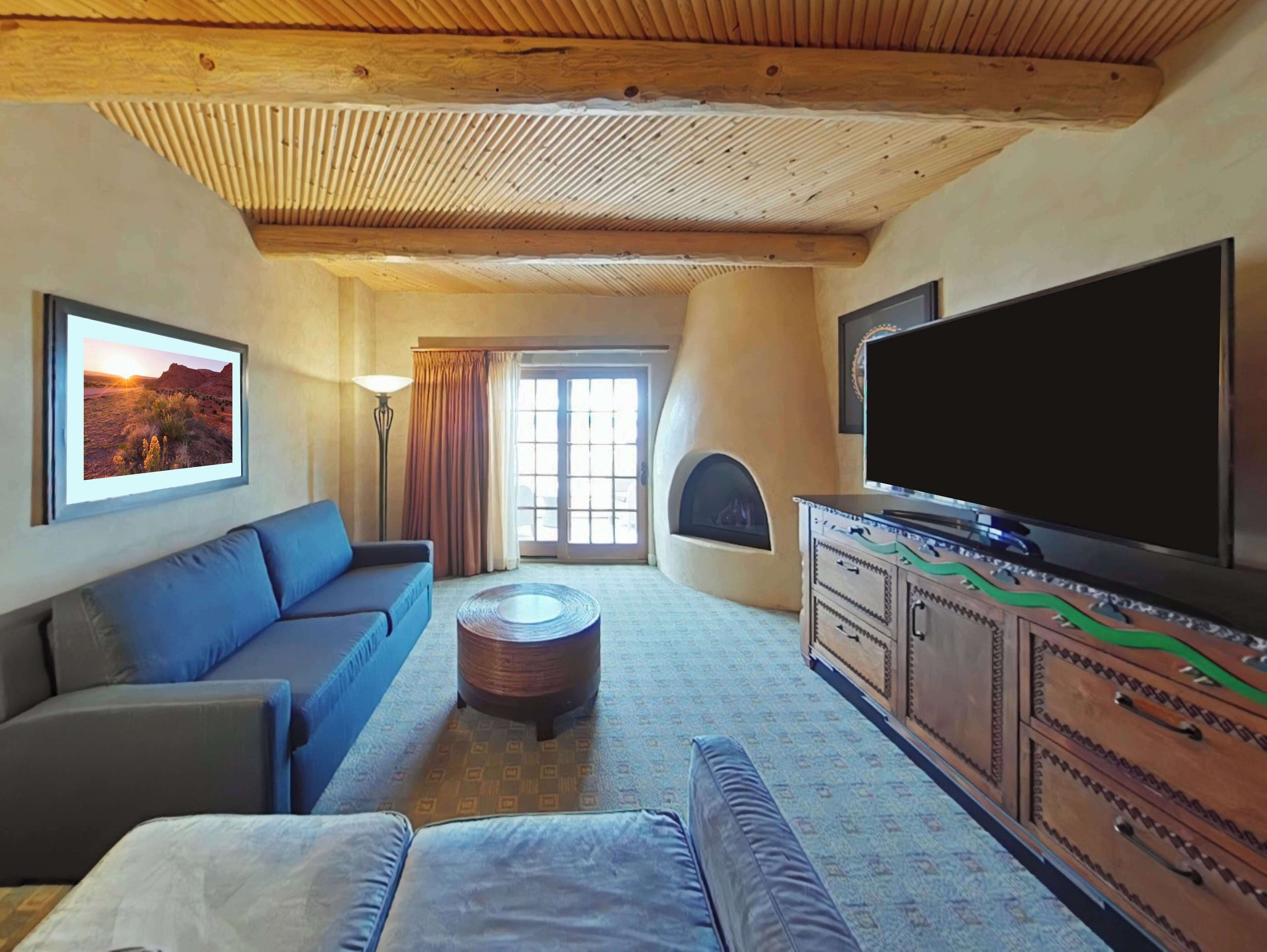 A cozy living room with a sofa, a coffee table, a flat-screen TV, and a fireplace.