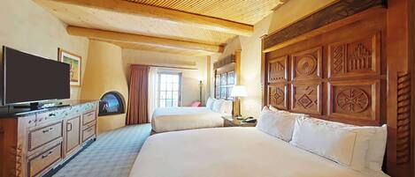 A hotel room with a large bed, a television, a dresser, and a window with curtains.