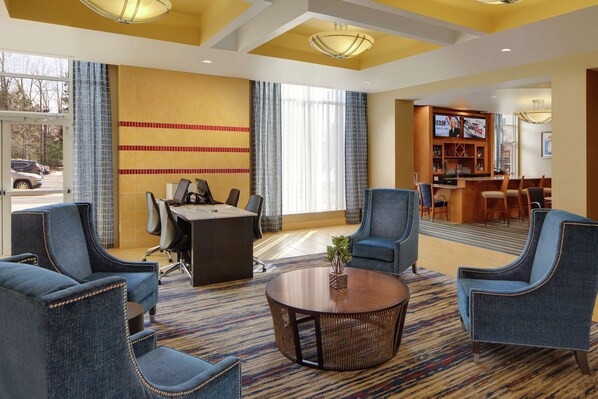 Un vestíbulo de hotel con recepción, zona de estar y bar.