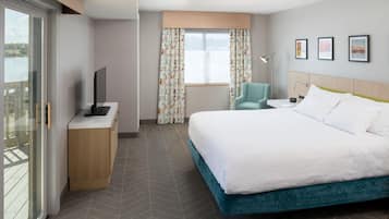 A hotel room with a bed, a desk, a chair, a TV, and a window with curtains.