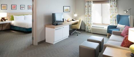 Una habitación de hotel con cama, escritorio, silla, televisor y sofá.
