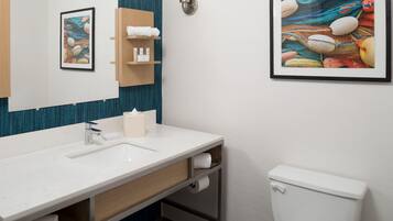 A bathroom with a white sink, a toilet, a towel rack, and a framed picture on the wall.