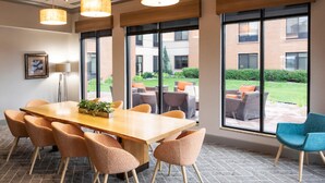 Un salón de conferencias con una mesa grande, sillas y ventanas amplias que dan a vistas del exterior.