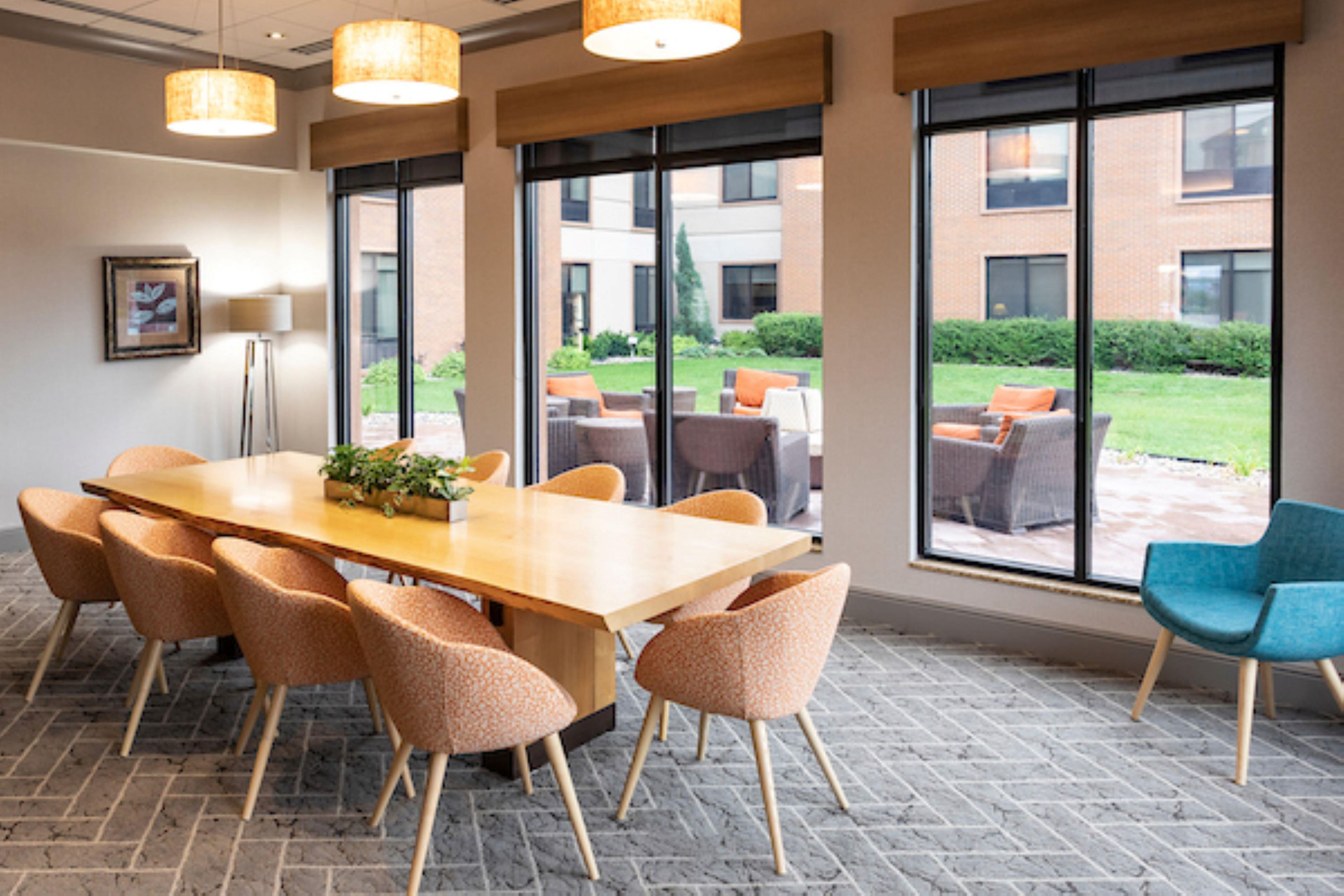 Un salón de conferencias con una mesa grande, sillas y ventanas amplias que ofrecen vistas al exterior.
