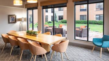 Un salón de conferencias con una mesa grande, sillas y ventanas amplias que ofrecen vistas al exterior.
